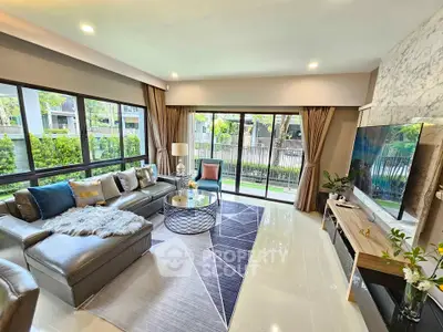 Luxurious living room with modern decor and large windows offering garden views.