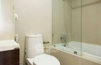 Modern bathroom with glass-enclosed bathtub and sleek fixtures.
