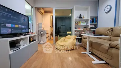 Cozy living room with modern decor, featuring a beige sofa, TV, and a bean bag chair.