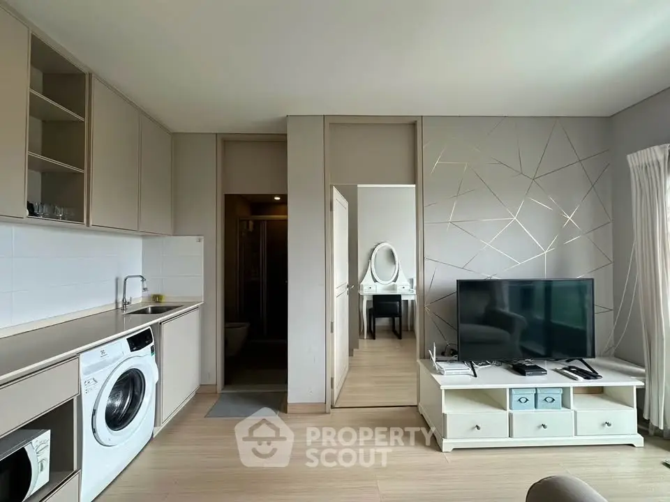 Modern living room with sleek design, featuring built-in cabinets, washing machine, and stylish TV setup.