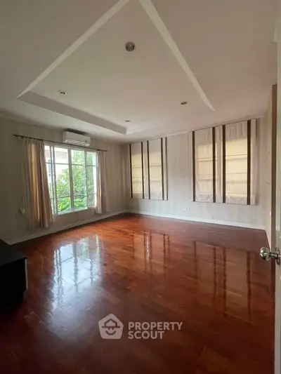Spacious empty living room with wooden flooring and large windows
