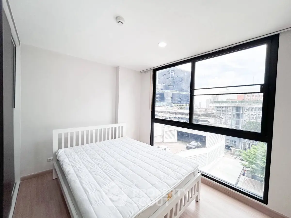 Bright bedroom with large window offering city views in modern apartment