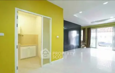 Spacious living room with vibrant yellow accent wall and large windows for natural light.