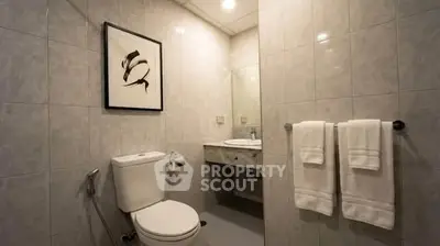 Modern bathroom with elegant tile design and framed artwork, featuring a sleek toilet and vanity area.