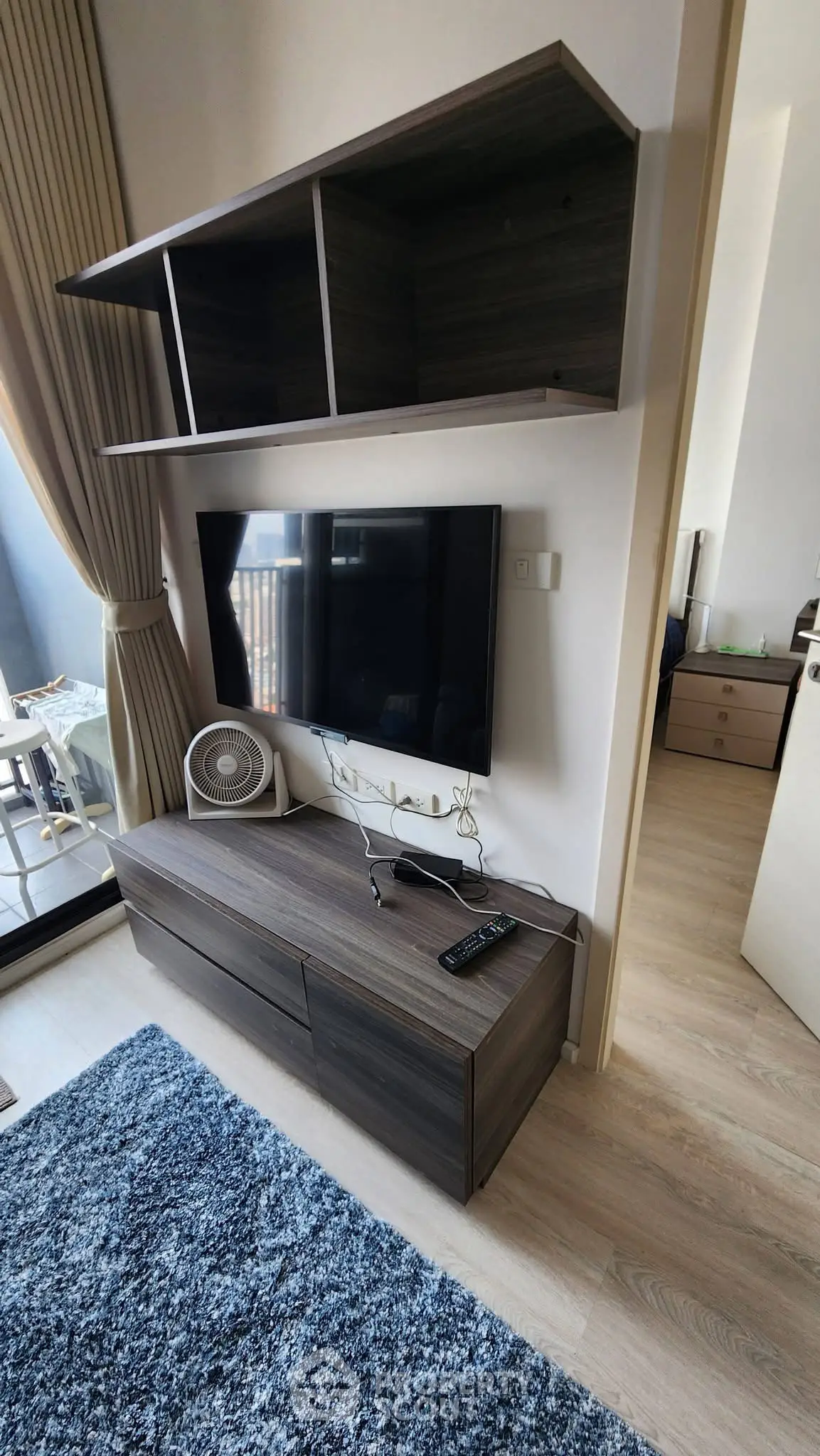 Modern living room with sleek TV unit and balcony view, perfect for urban living.