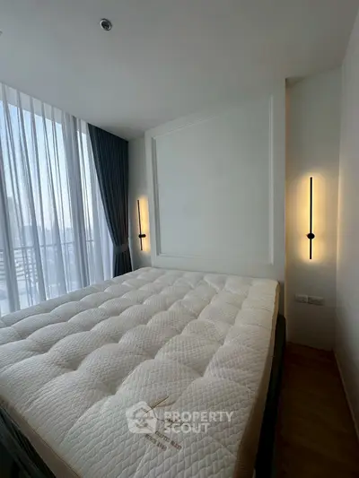 Modern bedroom with large window and stylish lighting, featuring a comfortable bed and elegant curtains.