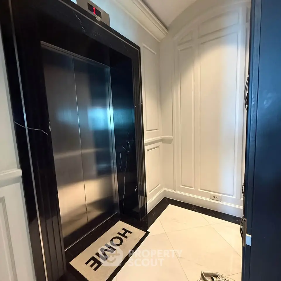 Luxurious elevator entrance with elegant white paneling and marble flooring, featuring a welcoming 'Home' doormat.