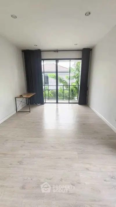 Spacious room with large window and wooden flooring, perfect for a bright and airy living space.