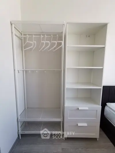Modern bedroom with open wardrobe and shelving unit, showcasing minimalist design and ample storage space.