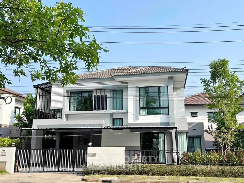 Modern two-story house with large windows and landscaped garden in a serene neighborhood.