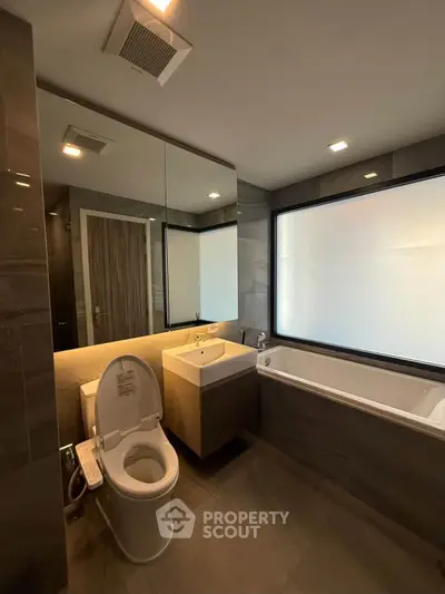 Modern bathroom with sleek fixtures and large frosted window for privacy.