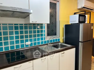 Modern kitchen with sleek appliances and vibrant blue tile backsplash.