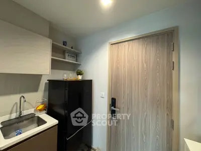 Modern kitchen with sleek cabinetry and compact fridge in a cozy apartment.