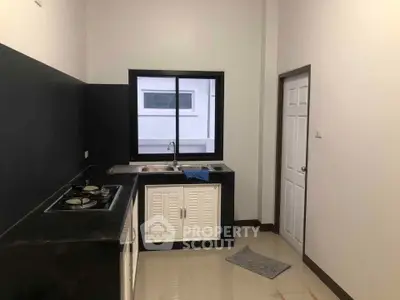 Modern kitchen with sleek black countertops and gas stove, featuring a large window for natural light.