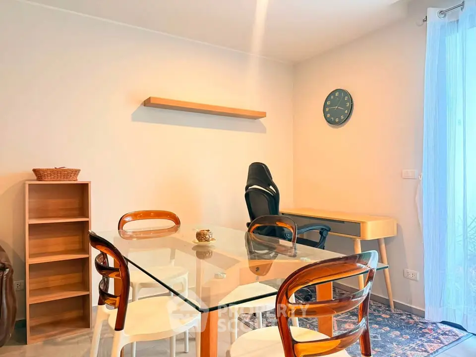 Modern dining area with glass table and stylish chairs, featuring a cozy study corner with desk and chair.