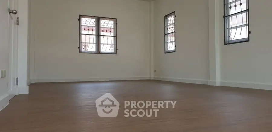 Spacious empty room with wooden flooring and large windows, ideal for customization.