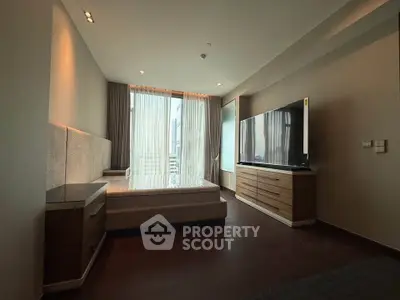 Spacious modern bedroom with large window and sleek furnishings in luxury apartment.