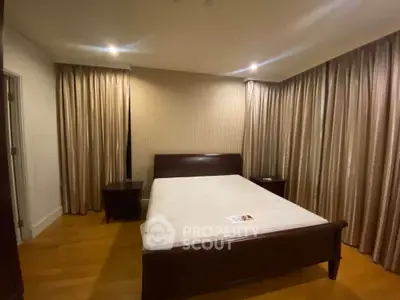 Spacious bedroom with elegant wooden flooring and luxurious curtains
