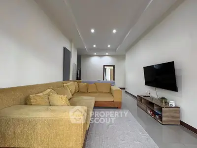 Spacious living room with modern sectional sofa and wall-mounted TV, perfect for relaxation and entertainment.
