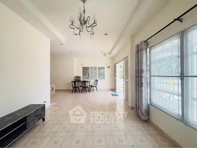 Spacious living room with elegant chandelier and large windows for natural light.