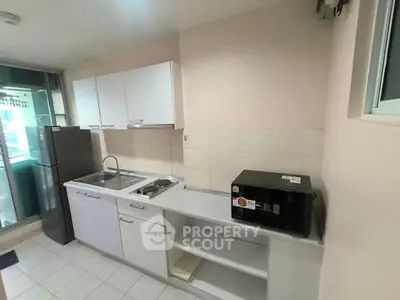 Modern kitchen with sleek white cabinets and appliances, featuring a microwave and fridge.