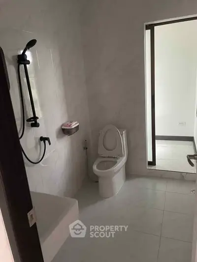 Modern bathroom with sleek fixtures and minimalist design, featuring a shower and toilet in a bright space.