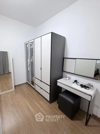 Modern bedroom with sleek wardrobe and vanity set, featuring minimalist design and ample storage space.