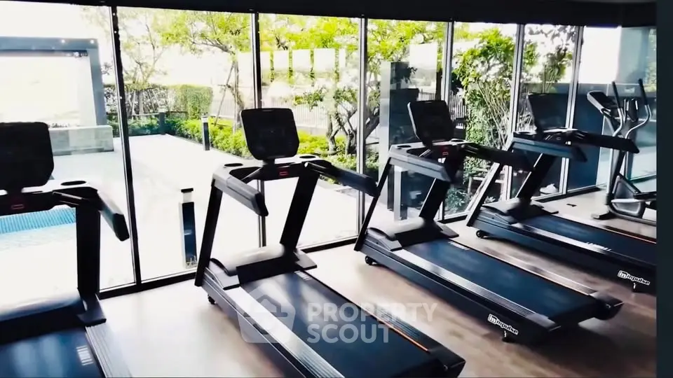 Modern gym with treadmills and large windows overlooking greenery