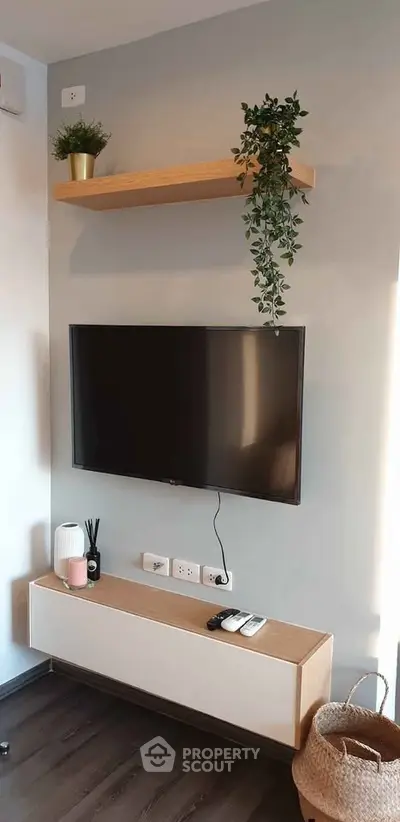 Modern living room with wall-mounted TV, floating shelf, and stylish decor.