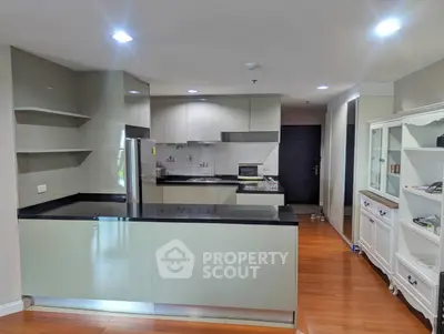 Modern kitchen with sleek cabinetry and open layout, featuring stainless steel appliances and hardwood flooring.