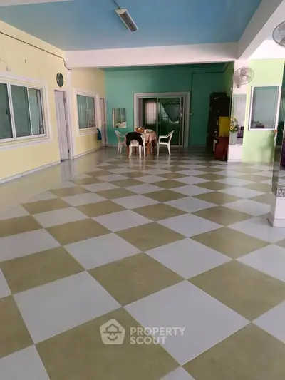 Spacious indoor common area with checkered flooring and seating, ideal for gatherings.