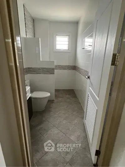Modern bathroom with tiled floor and window for natural light.