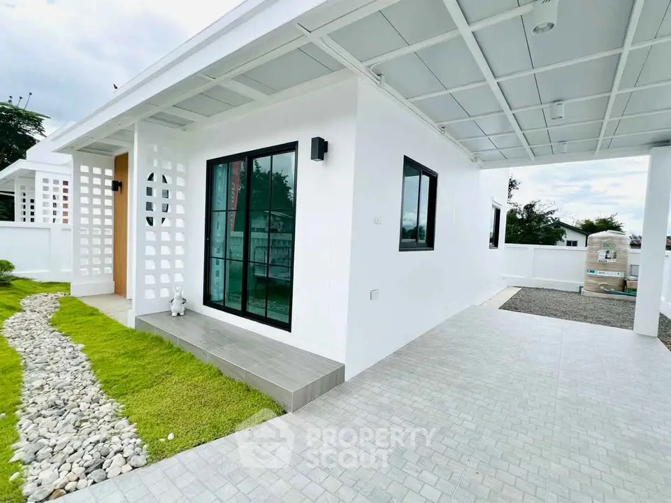 Modern white exterior of a stylish home with a sleek pathway and lush green lawn.