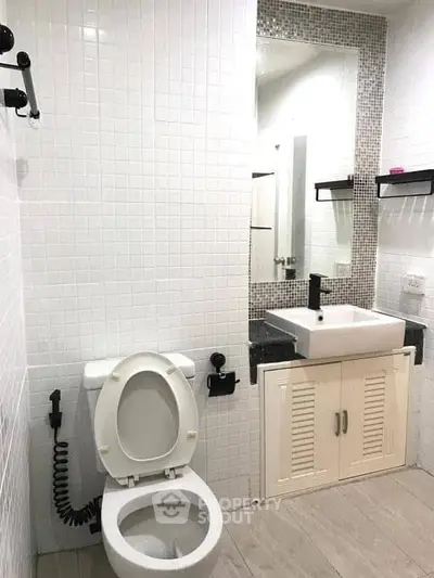 Modern bathroom with white tiles, sleek sink, and toilet in a stylish real estate property.