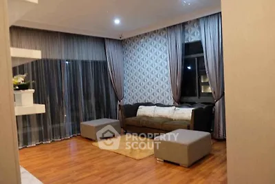 Elegant living room with modern decor and large windows, featuring stylish curtains and cozy seating area.