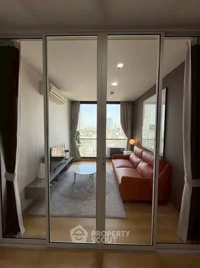 Modern living room with city view, featuring a stylish sofa and floor-to-ceiling windows.