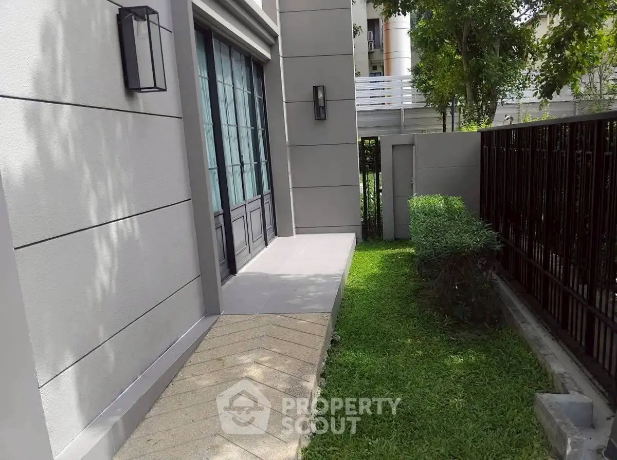 Modern townhouse exterior with lush green garden and sleek design