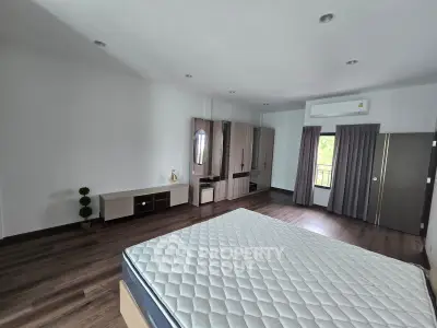 Spacious bedroom with modern decor and large window for natural light.
