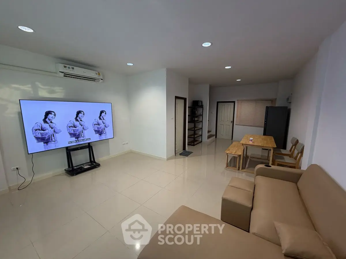 Spacious living room with modern furniture and large TV, ideal for relaxation and entertainment.