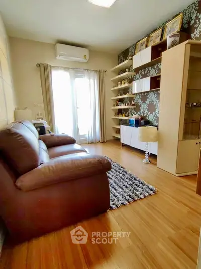 Cozy living room with leather sofa, wooden flooring, and stylish shelving.