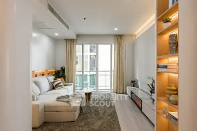 Modern living room with cozy sectional sofa and elegant decor, featuring large windows and stylish shelving.