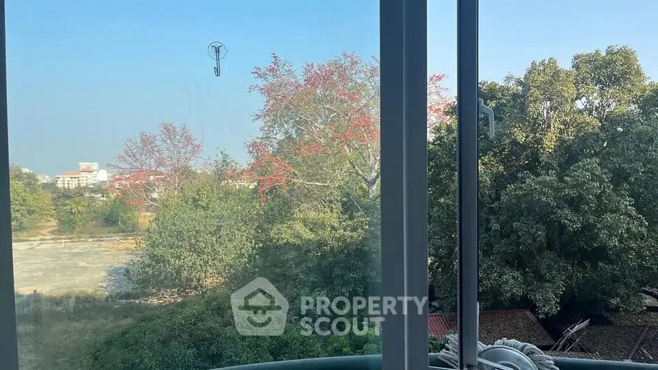 Stunning view from a window overlooking lush greenery and distant buildings, perfect for nature lovers.