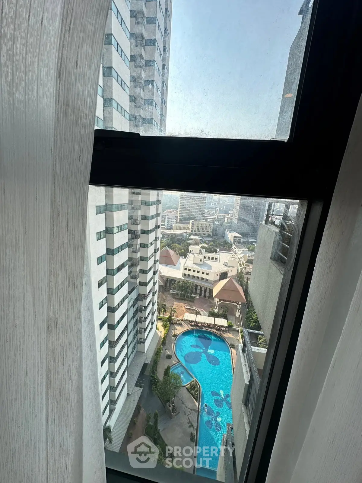 Stunning high-rise view with pool and cityscape from apartment window