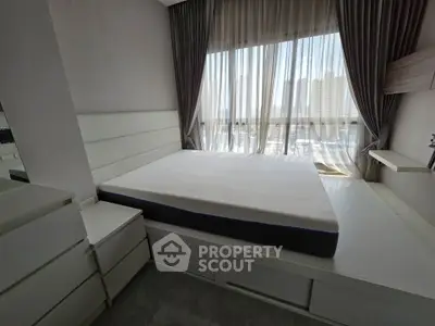 Modern bedroom with large window and stylish curtains, featuring a sleek bed and ample storage space.