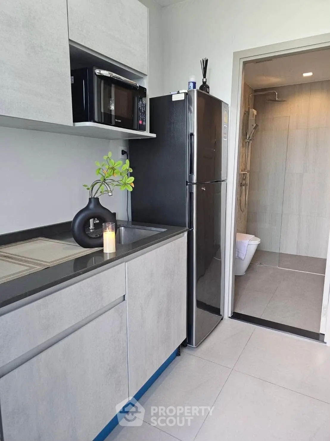 Modern kitchen with sleek cabinetry and stainless steel appliances adjacent to a stylish bathroom.