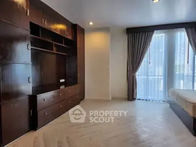 Spacious bedroom with elegant wooden built-in wardrobe and large window with curtains.