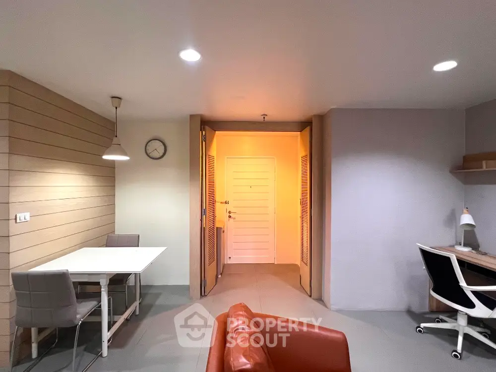 Modern apartment interior with dining area and study space, featuring sleek furniture and ambient lighting.