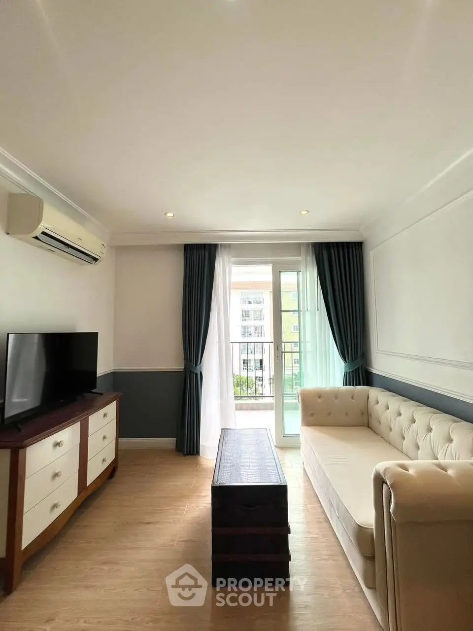 Charming living room with elegant sofa, TV, and balcony view in modern apartment.