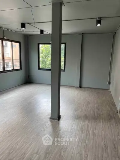 Spacious room with modern flooring and large windows, ideal for versatile use.
