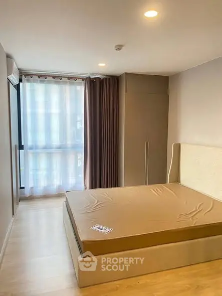 Spacious bedroom with large window and modern furnishings in a stylish apartment.